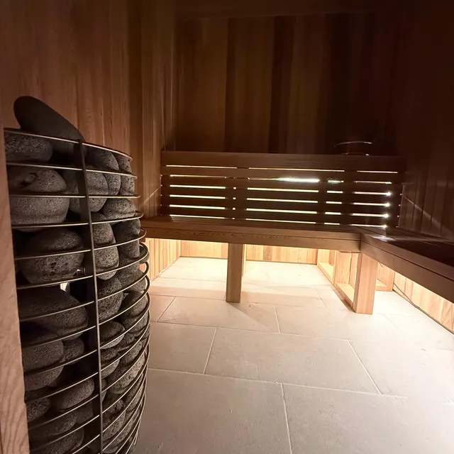 Cedar sauna interior with a stone heater and wood benches